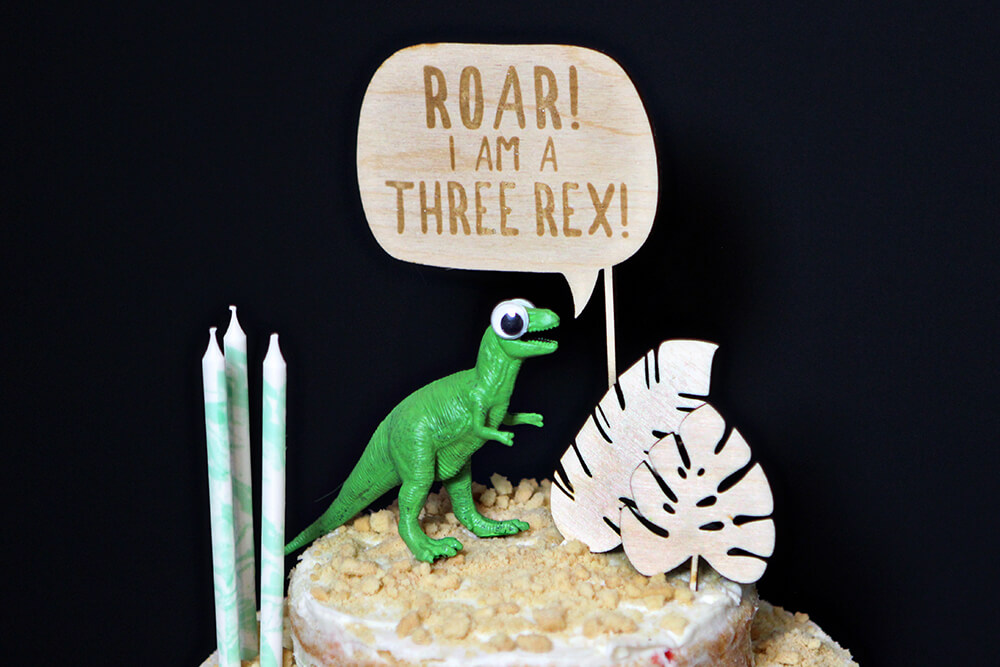 three rex cake topper for a cake at a dinosaur party